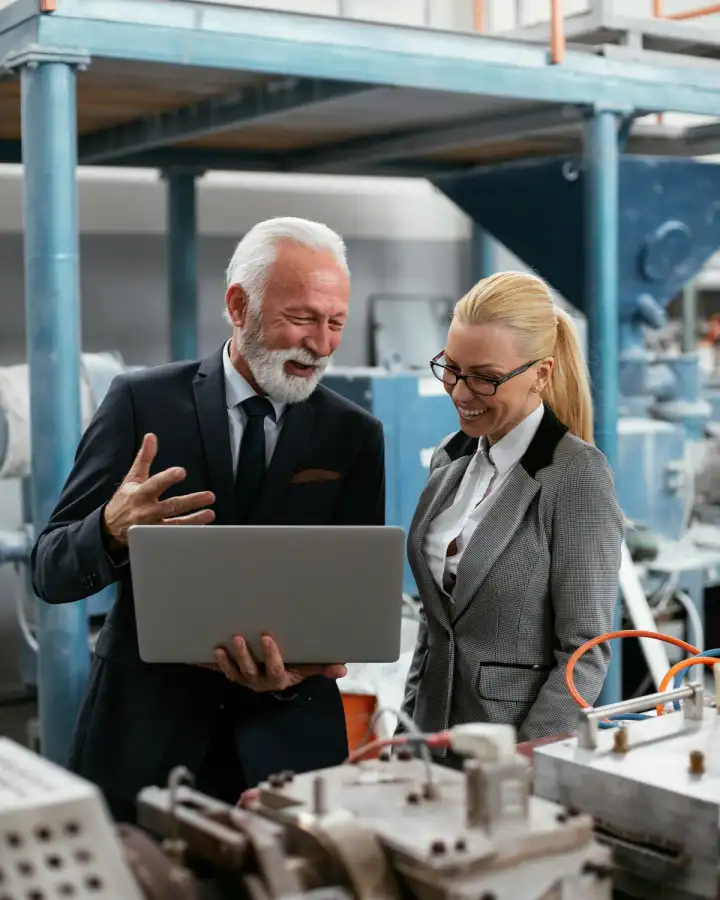 Two professionals reviewing information on a laptop in an industrial setting
