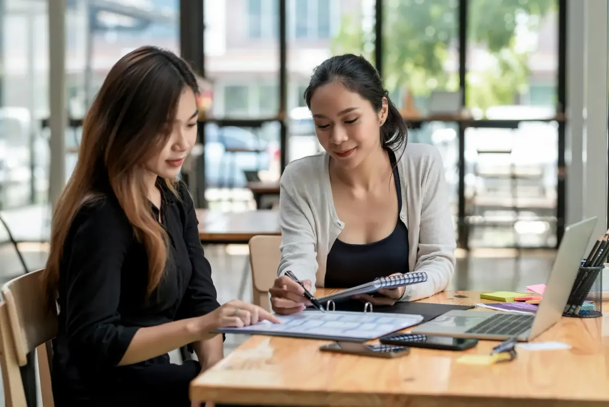 Two colleagues reviewing notes and planning materials together