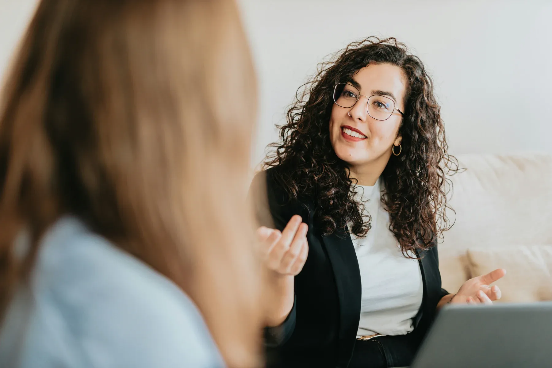 Two professionals talk in a bright meeting space.